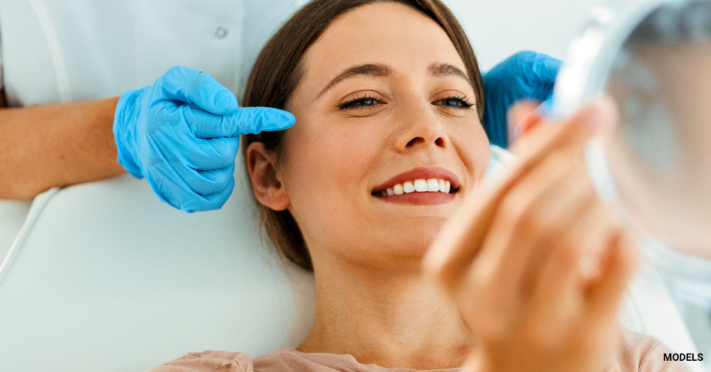 Woman looking in mirror, happy about her plastic surgery results (MODELS)